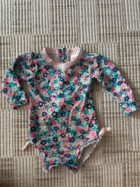 Rufflebutts Floral Print Long-sleeve baby one piece swimsuit.